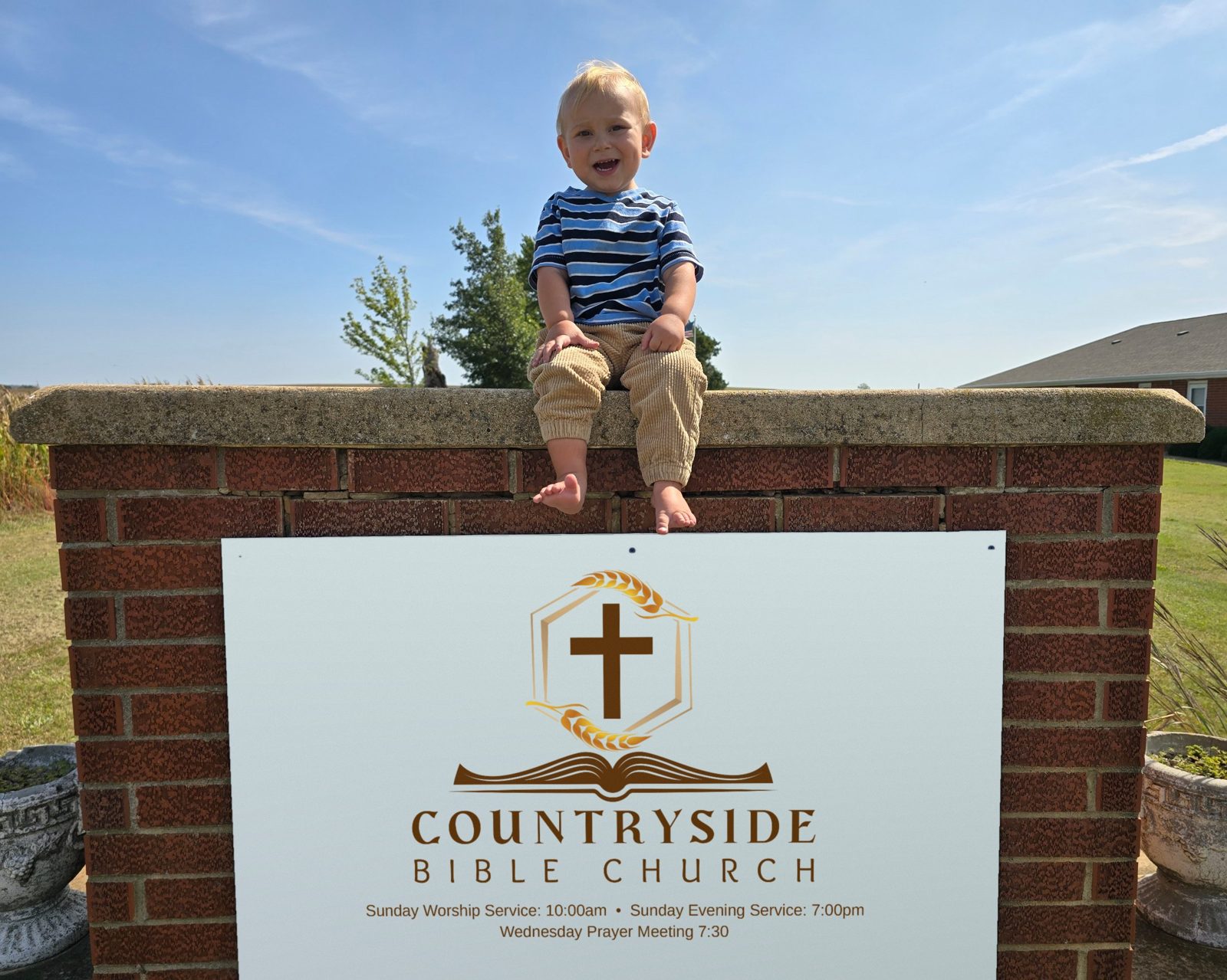 A smiling toddler sitting on top of the Countryside Bible Church sign